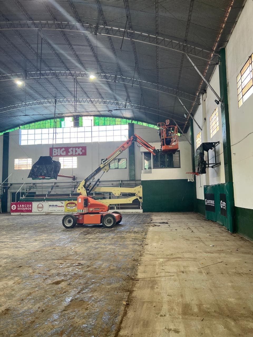 Techo metálico del gimnasio del Club Pacífico antes de la aislación, con plataforma elevadora sobre la cancha