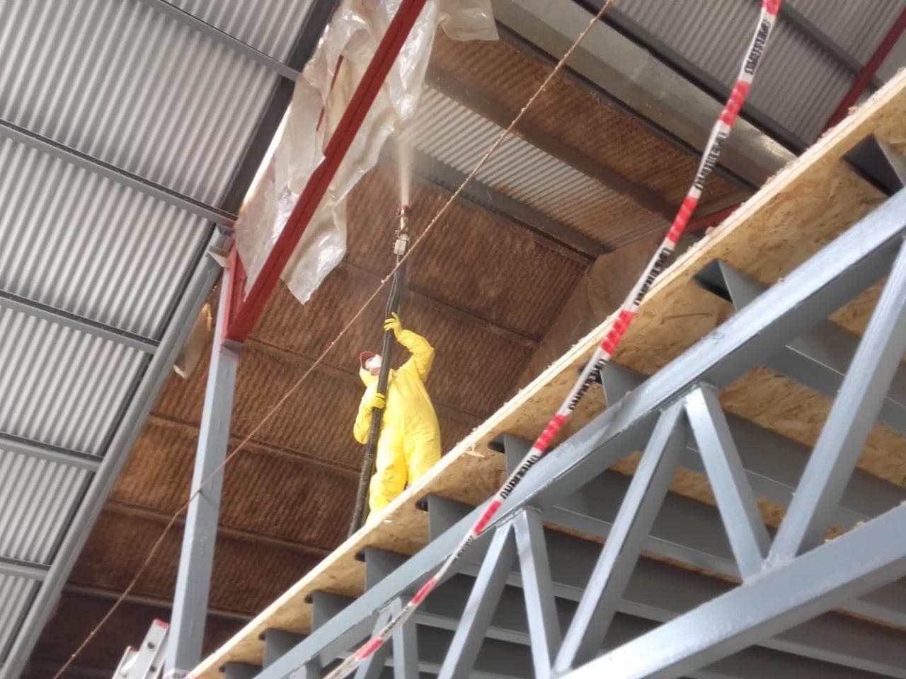 Operario proyectando celulosa en techo de galpón, Tandil